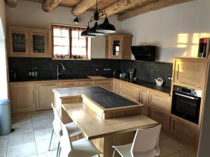 cocina con mesa de madera y sillas blancas en Les Hauts de Cassagnas, en Saint-Julien-de-Cassagnas