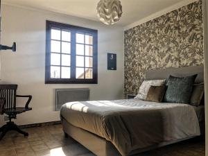 1 dormitorio con cama, ventana y lámpara de araña en Les Hauts de Cassagnas, en Saint-Julien-de-Cassagnas