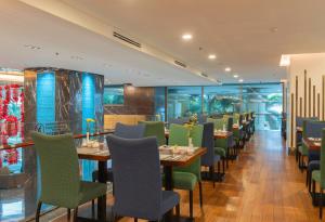 un restaurante con sillas verdes, mesas y ventanas en Havana Nha Trang Hotel, en Nha Trang