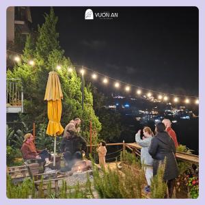 um grupo de pessoas sentadas à volta de uma fogueira à noite em Vuon An Villa - Best pine alley view, garden, BBQ em Ấp Ða Lợi