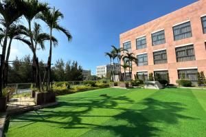 a lawn in front of a building with palm trees at JANDA Golden Tulip Hotel in Wuqi