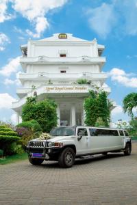 una limusina estacionada frente a un edificio blanco en Hotel Royal Grand Paradise, en Kelaniya