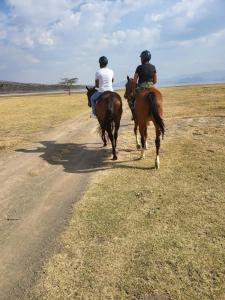 two people riding horses down a dirt road at Lake Elementaita Manor in Gilgil
