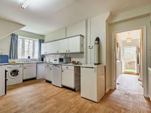 a kitchen with white appliances and a wooden floor at 4 Bed in Uckfield BT021 in Buxted