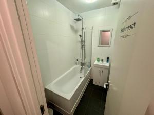 Un baño blanco con bañera y lavabo. en Cosmopolitan Comfort Private Bedrooms in Euston 106, en Londres 36 fotos más