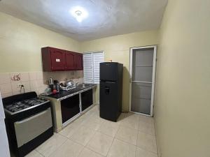a kitchen with a black refrigerator and a sink at Casa en Villa Marchena azua in Azua de Compostela