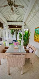 Bali Canggu 3 bdr villa Pool Garden, Discounted في كيروبوكان: فناء مع طاولة وكراسي ومروحة سقف