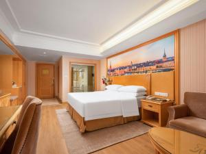 1 dormitorio con 1 cama blanca grande y 1 sofá en Vienna International Hotel Wuhan Jiefang Avenue, en Wuhan