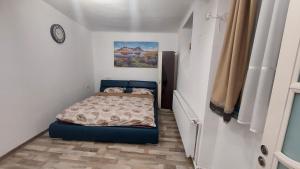a small bedroom with a bed and a clock on the wall at Apartament Diaconu Coresi (Piata Sfatului) in Braşov