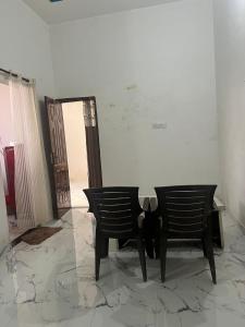 - une chambre avec deux chaises, une table et une porte dans l'établissement Grewal homestay, à Jalandhar