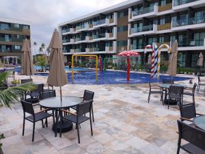 a pool with tables and chairs and a playground at Mana beach class experience in Porto De Galinhas