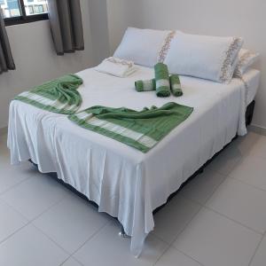Una cama blanca con una manta verde. en Mana beach class experience en Porto De Galinhas