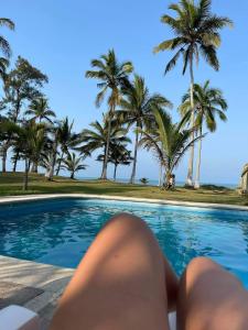 une personne se posant au bord d'une piscine bordée de palmiers dans l'établissement Vikinga casa de playa, à Monte Gordo