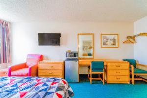 Schlafzimmer mit einem Bett, einem Schreibtisch und einem Stuhl in der Unterkunft HomeTown Inn By OYO Texhoma, OK in Texhoma