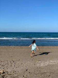a girl running on the beach with a frisbee at Vikinga casa de playa in Monte Gordo
