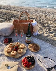 un picnic en la playa con comida y una botella de vino en Vikinga casa de playa, en Monte Gordo