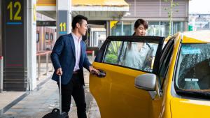 un uomo e una donna in piedi accanto a un taxi giallo di SCN Pet-friendly Hotel โรงแรมรับสัตว์เลี้ยง a Ban Chang