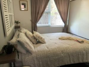 a bedroom with a bed with pillows and a window at MRS BROWN’s COMFY CITY PAD in Norwood