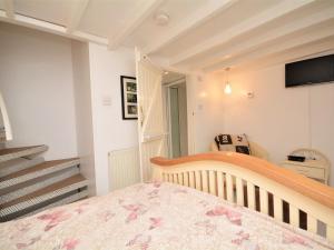 1 dormitorio con cuna, TV y escaleras en 1 bed property in Fowey SYBAR, en Saint Blazey