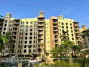 a large white building with palm trees in front of it at Brand New l Stylish and Spacious 2BR in Madinat Jumeirah in Dubai