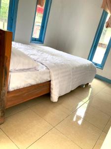 - un lit avec une couette blanche installée dans une chambre dans l'établissement Batubutir homestay, à Midang