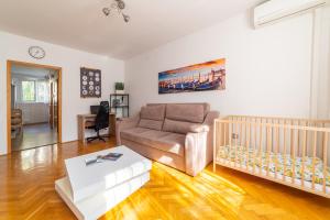 ein Wohnzimmer mit einem Sofa und einem Kinderbett in der Unterkunft ""Comfort 14'' in Miskolc