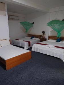 a room with three beds with green curtains on them at Aurora Echo Villa in Matara