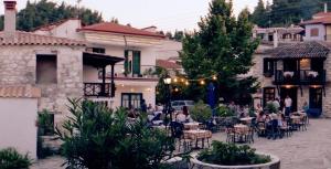 a group of people sitting at tables in a courtyard at Casagrande Studio in Kriopigi