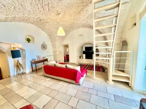 een woonkamer met een rode bank en een trap bij Trulli Moon in Alberobello