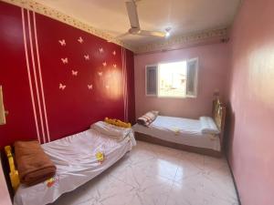 2 łóżka w pokoju z czerwonymi ścianami w obiekcie Mayane home w mieście Luksor