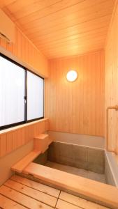 a bathroom with a bath tub and a window at Kusatsu onsen Futabaya in Kusatsu