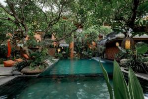 a swimming pool in a garden with trees and plants at Fourteen Roses Boutique Hotel, Kuta in Legian +155 photos