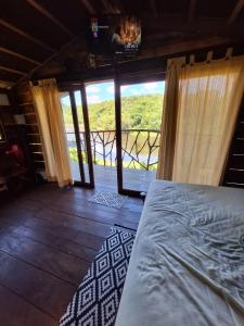 a bedroom with a bed and a large window at Moradia da Mata in Nilo Peçanha