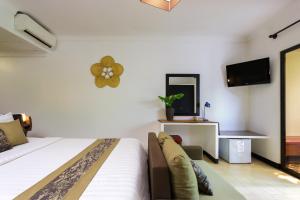 ein Schlafzimmer mit einem Bett, einer Couch und einem Fernseher in der Unterkunft La Niche D'angkor Boutique Hotel in Siem Reap