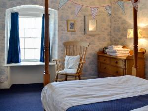 een slaapkamer met een bed, een stoel en een raam bij Hornblower - Hddv in Ilfracombe