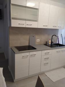 una cocina con armarios blancos y fregadero en Casa Mont Blanc apartament 1, en Cavnic