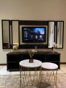 ein Wohnzimmer mit 2 Tischen und einem Flachbild-TV in der Unterkunft Thorntree Self Catering Apartment, Witbank in Witbank
