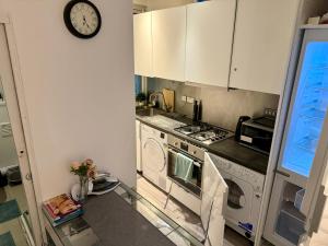 a kitchen with a stove and a clock on the wall at Downtown Chic Private Bedrooms in King's Cross 4 in London