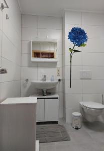 een badkamer met een wastafel, een toilet en een blauwe bloem bij Voslapper Seeluft in Wilhelmshaven