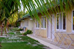 a building with chairs and palm trees in front of it at Trikora Beach Club and Resort in Telukbakau