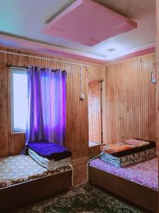 two beds in a room with purple curtains at BODHI VILLA in Sombāri