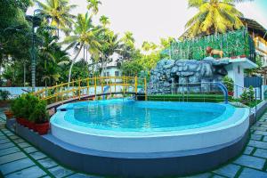 einem Pool mit einer Statue vor einem Resort in der Unterkunft Lake Palace Family Resort Kumarakom in Kumarakom