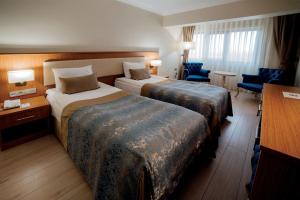 GolbasıにあるPatalya Lakeside Resort Hotelのベッド2台とデスクが備わるホテルルームです。