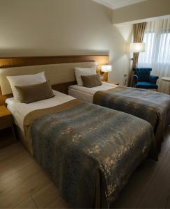 una habitación de hotel con 2 camas y una silla en Patalya Lakeside Resort Hotel, en Golbası