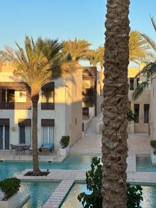 a palm tree in front of a building with a pool at Bright & Lovely 2 Beds Apartment in Scarab Club, El Gouna in Hurghada