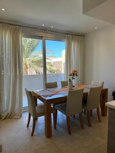 ein Esszimmer mit einem Tisch, Stühlen und einem Fenster in der Unterkunft Bright & Lovely 2 Beds Apartment in Scarab Club, El Gouna in Hurghada