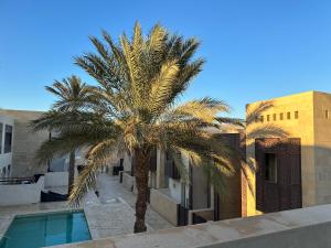 a palm tree in front of a building with a swimming pool at Bright & Lovely 2 Beds Apartment in Scarab Club, El Gouna in Hurghada