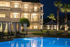 a villa with a swimming pool at night at San Giovanni Beach Resort and Suites in Lefkada Town