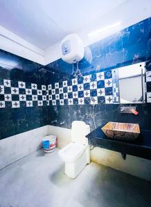 a bathroom with a toilet and a black and white tiled wall at The Nizamuddin palace in New Delhi