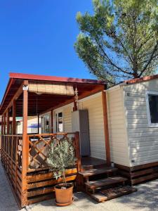 a tiny house with a porch and a deck at Mobile home "Sun" Jezera Village , otok Murter in Jezera